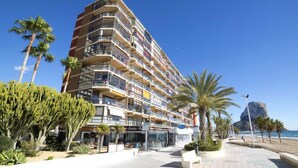 A multi-story hotel with balconies, located near a beach with palm trees and a rocky outcrop. - Calpemar by Interhome (Calpe/Calp)