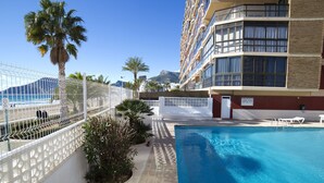 A pool area with a clear view of the sea, a fenced walkway, and a building with balconies. - Calpemar by Interhome (Calpe/Calp)