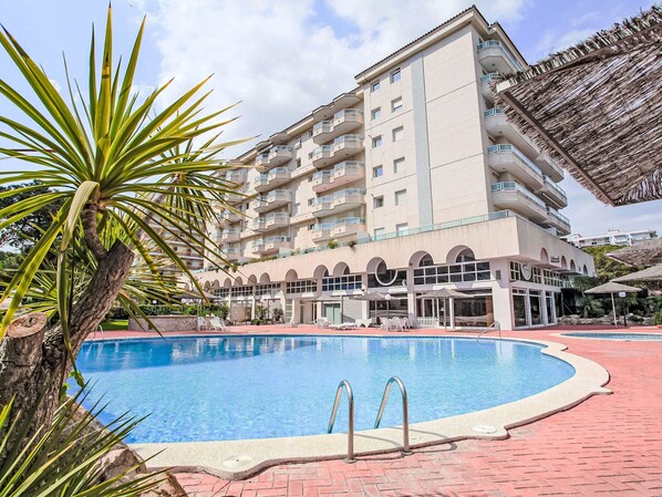 Un hotel con piscina, diversi balconi e una zona ristorazione.