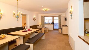 A modern hotel room with a dining area, a sofa, a table with benches, and a view of the outside. - Apartment Alpin by Interhome (Sölden)