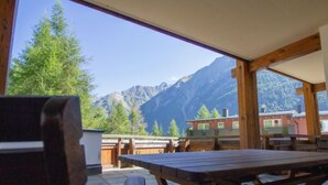 A wooden table and chairs in a room with large windows overlooking a mountain landscape. - Apartment Alpin by Interhome (Sölden)