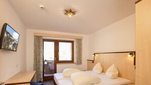 A hotel room with a bed, a desk, a chair, a TV, and a window with curtains. - Apartment Alpin by Interhome (Sölden)