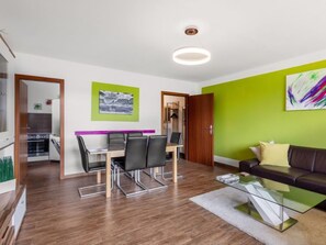 A modern living room with a glass coffee table, a leather sofa, and a dining area with a table and chairs.