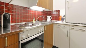 A compact kitchen with a stove, oven, sink, and a refrigerator. - Apartment Apollo by Interhome (Zermatt)
