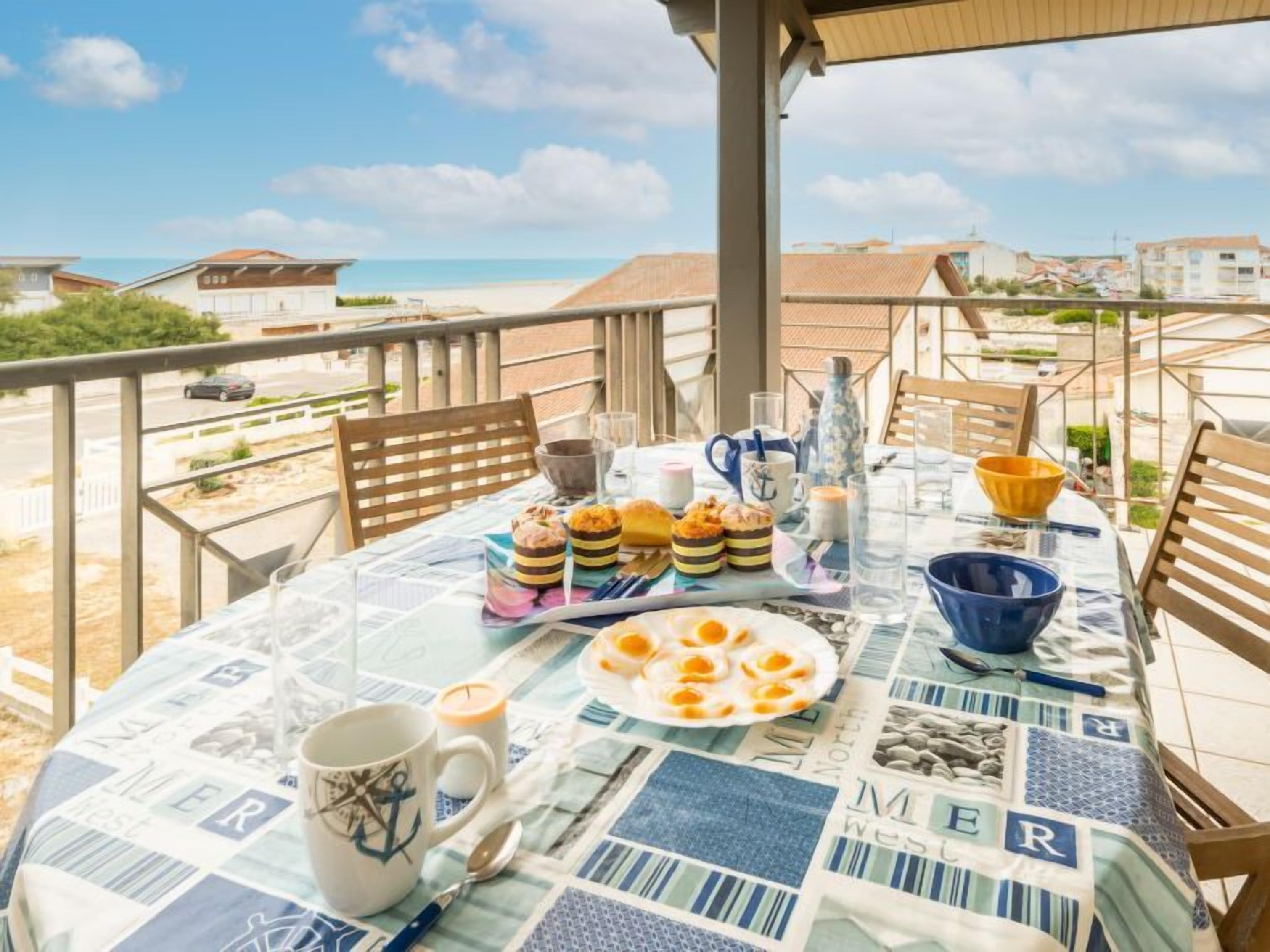 A table set for breakfast on a balcony overlooking a beach.