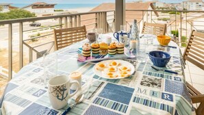 Een ontbijttafel op een balkon met uitzicht op het strand.