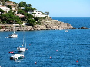 Una zona costera amb vaixells a l'aigua, penya-segats rocosos i edificis damunt la vessant.