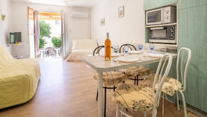 Un espace de vie compact comprenant un coin repas, une kitchenette et un lit.