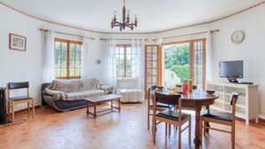 A cozy living room with a sofa, chairs, a dining table, and a television.