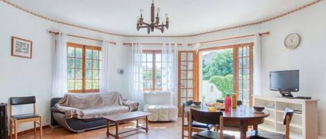 A cozy living room with a sofa, chairs, a dining table, and a television.