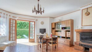 A spacious living room with a fireplace, a dining area, and a kitchen with wooden cabinets.