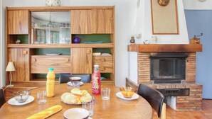 A dining area with a round wooden table set for breakfast, including bread, pastries, and beverages.