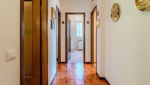 A hallway with tiled flooring, wooden doors, and framed pictures on the walls. - Apartment Marta by Interhome (Cerano d'Intelvi)
