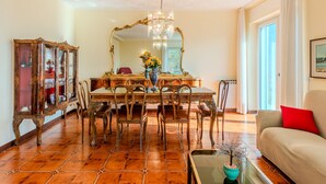 A dining area with a wooden table, chairs, and a large mirror. There is a chandelier above the table and a cabinet with glass doors to the left. - Apartment Marta by Interhome (Cerano d'Intelvi)