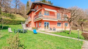 A two-story house with a balcony, a front porch, and a small garden area with outdoor furniture. - Apartment Marta by Interhome (Cerano d'Intelvi)