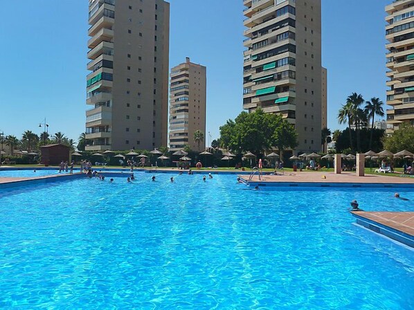 Piscina rodeada por edifícios residenciais altos com varandas.