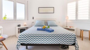 A bedroom with a bed, a nightstand, a chair, and a window. - Club Nautic by Interhome (Empuriabrava)