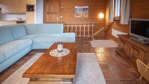 Una sala de estar con una mesa de centro de madera, un sofá, un televisor y un cuadro en la pared.