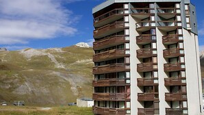Un hotel de varios pisos con balcones, frente a un paisaje montañoso.