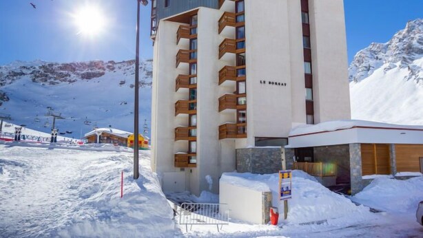 Un hotel moderno con una pista de esquí al fondo.