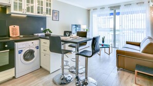 A modern kitchen with a built-in washing machine, a dining area with a table and chairs, and a seating area with a sofa. - Le Beach Garden by Interhome (Cannes)