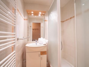 A bathroom with a white sink, mirror, and towel rack.