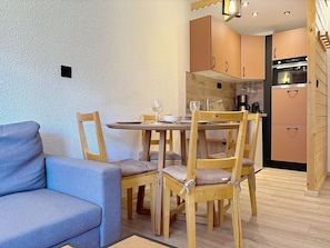 Un espace de vie compact comprenant un coin repas, un canapé et une kitchenette.