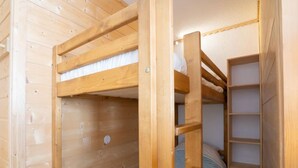 Een slaapkamer met stapelbedden, houten wanden en een ingebouwde plank.