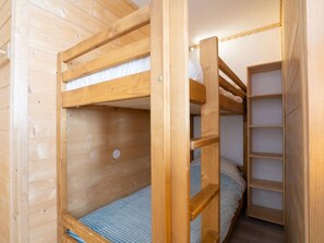 Dormitorio con literas, paredes de madera y una estantería empotrada.