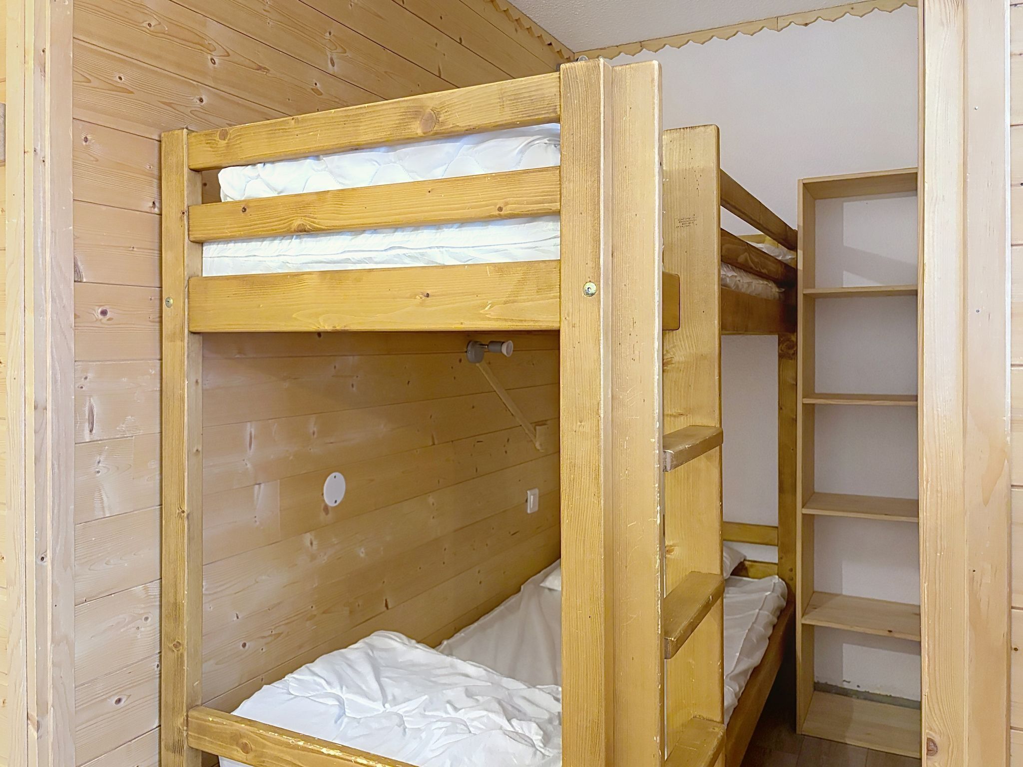 Un lit superposé avec une structure en bois et un lit inférieur doté d’un matelas.