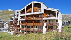 Een hotel met meerdere verdiepingen en balkons, met een skilift op de achtergrond en een bergachtig landschap.