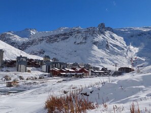 Un pueblo en la montaña cubierto de nieve, con edificios y un telesilla.