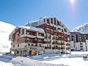 Een hotel met meerdere verdiepingen, balkons, een skiwinkel en een restaurant.