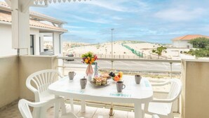 A balcony with a table set for breakfast, overlooking a beach and a road. - Patguyflor by Interhome (Mimizan)