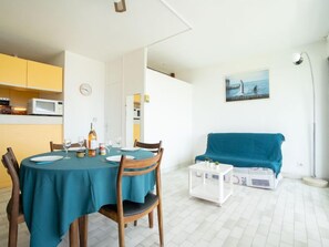 A compact living space with a dining area, kitchenette, and a sofa.