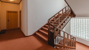 Una escalera con barandilla de madera y un ventanal de bloques de vidrio.