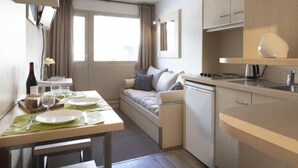 A compact hotel room with a kitchenette, a dining area, and a sofa.