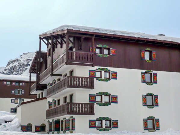 A multi-story building with balconies and traditional window designs, set against a snowy mountain backdrop. - Chalet Club (Val Claret) by Interhome (Tignes)