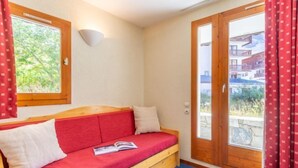 A cozy room with a wooden bench, red cushions, a white pillow, and a book on the bench. - Chalet Club (Val Claret) by Interhome (Tignes)