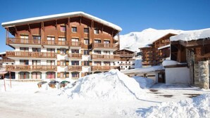 A multi-story hotel with wooden balconies and a snow-covered mountain in the background. - Chalet Club (Val Claret) by Interhome (Tignes)