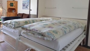 A double bed with a patterned duvet, a wooden cabinet, and a framed picture on the wall. - Apartment Castor by Interhome (Täsch)