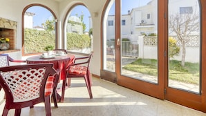 Un'area da pranzo con un tavolo rotondo e sedie, ampie finestre ad arco e vista su una zona residenziale.