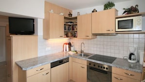 A compact kitchen with wooden cabinets, a built-in microwave, a stove, and a sink. - Apartment Plank by Interhome (Kaltenbach)