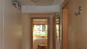A hallway with a wooden door, a radiator, and a window with a view of greenery. - Apartment Plank by Interhome (Kaltenbach)