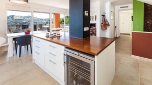 A modern kitchen with a central island, a built-in oven, and a view of the city.