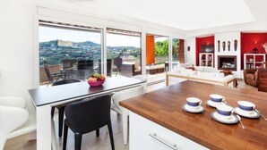 A modern kitchen with a dining area, large windows, and a view of the city.