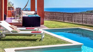A poolside area with lounge chairs and a small seating area overlooking the ocean.