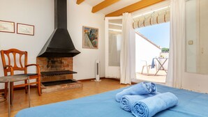 A room with a bed, a fireplace, a chair, and a view to an outdoor area. - Delta 1 by Interhome (L'Escala)