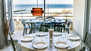 Mesa de comedor para cuatro con vista al océano y a la playa.