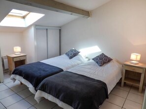 Ein Schlafzimmer mit zwei Betten, einem Oberlicht und Nachttischlampen.
